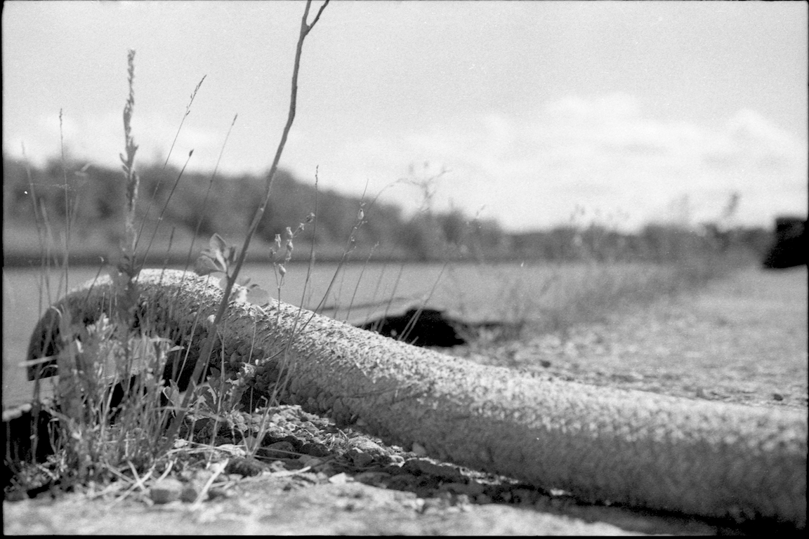 A black-and-white photo of a large cable on the ground.